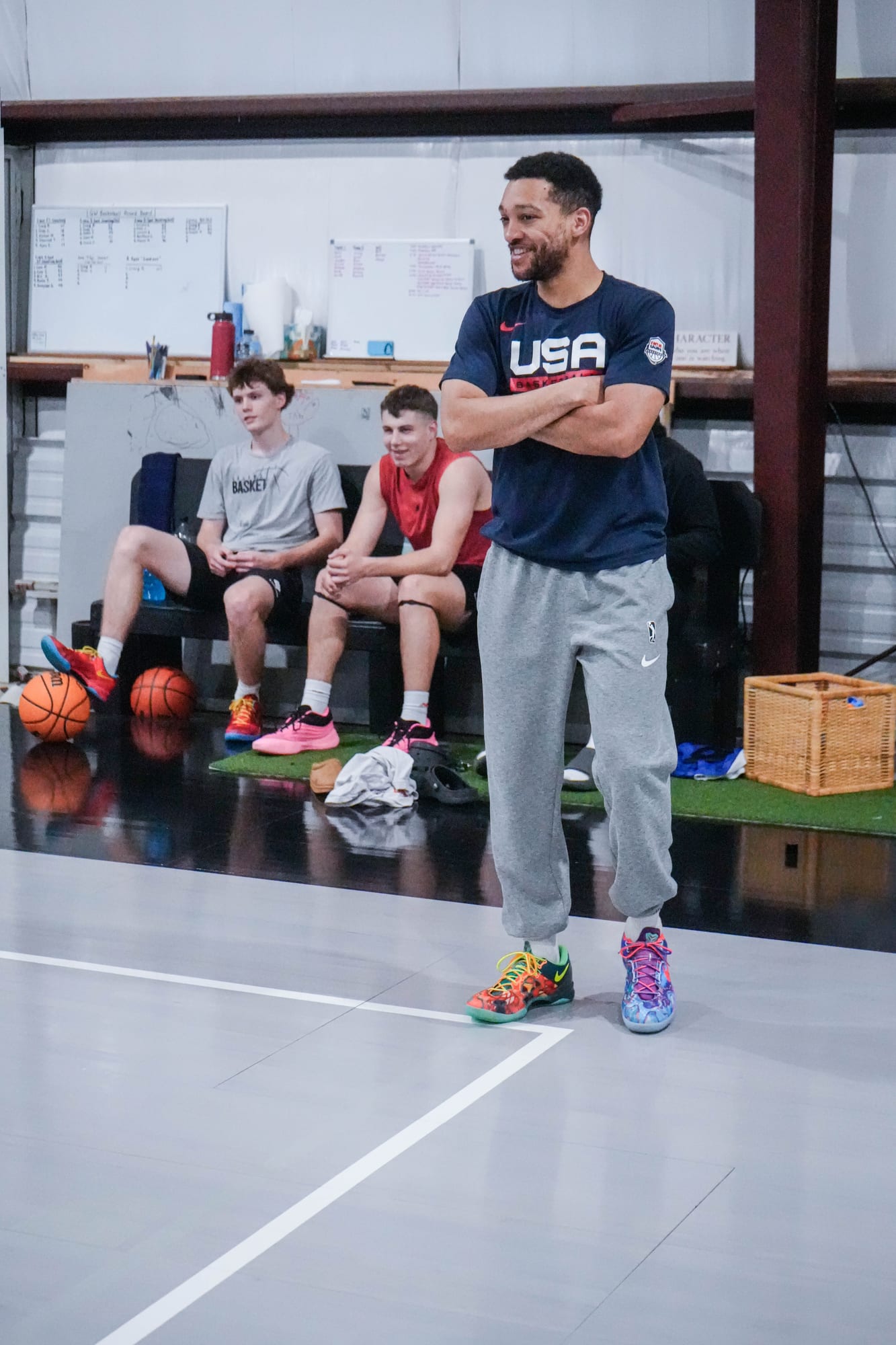 Coach Kyle Randall on the court with players and the session board behind him
